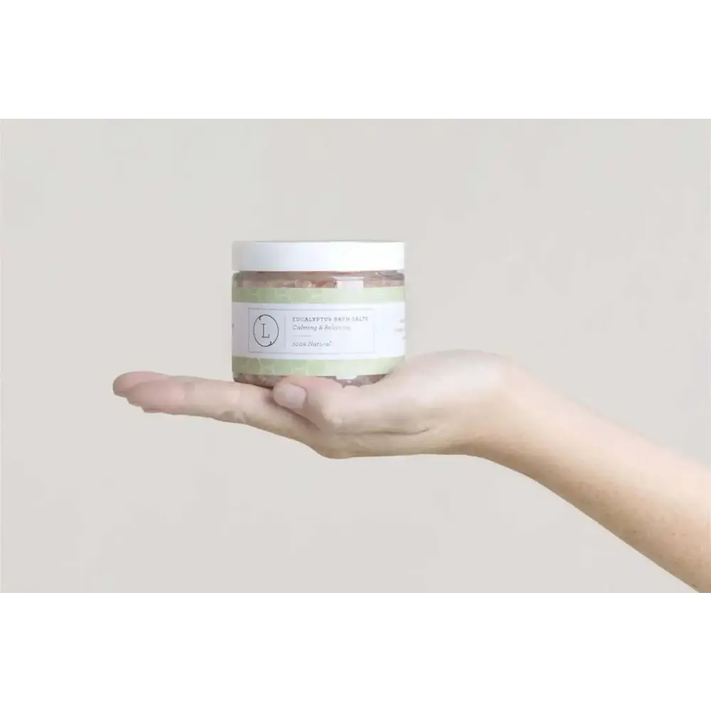 A clear glass jar with a white lid and yellow label containing a natural clay mask for body skincare products and home spa