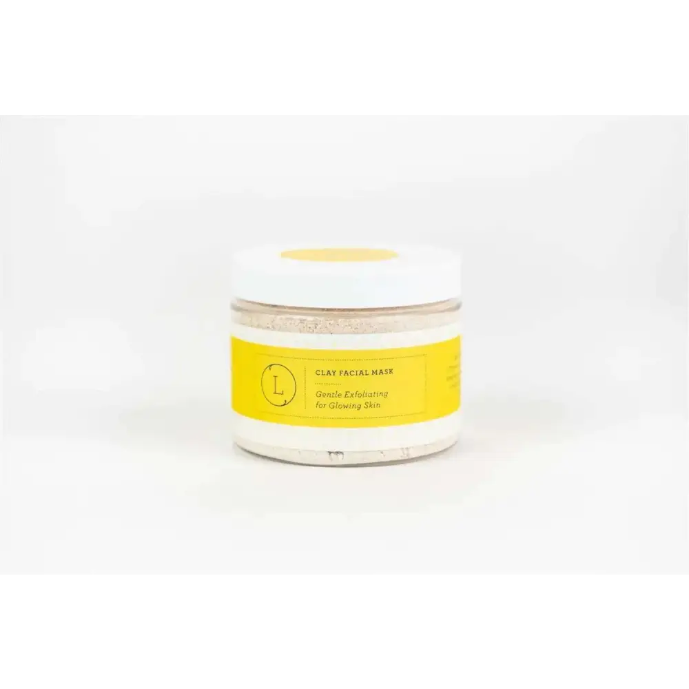 A clear glass jar with a white lid and yellow label containing a natural clay mask for body skincare products and home spa