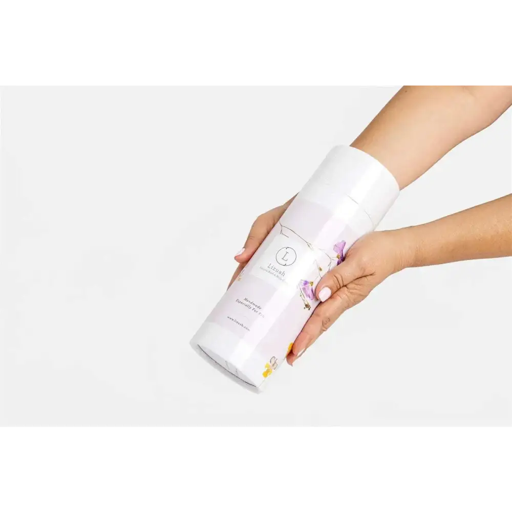A white cylindrical container of lizash natural clay mask with floral design for body skincare products and home spa use