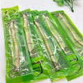 Five light beige natural miswak tooth cleaning sticks individually wrapped in green decorative plastic for tooth cleaning