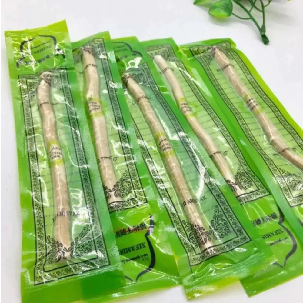 Five light beige natural miswak tooth cleaning sticks individually wrapped in green decorative plastic for tooth cleaning