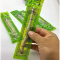 A hand holds a green-packaged natural miswak tooth cleaning stick with ornate black and gold arabic labels