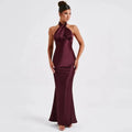 A sleek floor-length burgundy satin gown with a halter neckline and fitted silhouette elegant backless sleeveless design