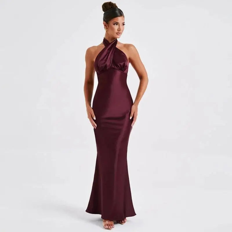 A sleek floor-length burgundy satin gown with a halter neckline and fitted silhouette elegant backless sleeveless design
