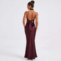 Sleek back view of a maroon elegant backless sleeveless satin gown with a fitted silhouette and tied bow at the waist