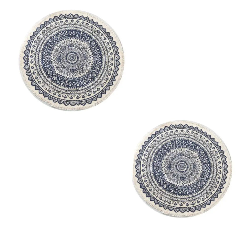 Two cream-colored circular carpet floor mats with navy mandala ethnic style patterns and fringed edges