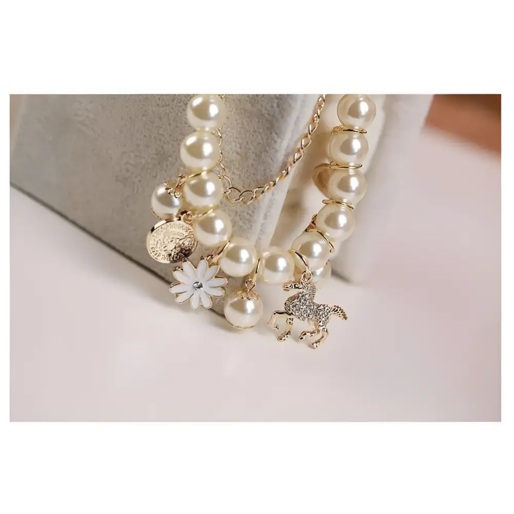 Navy pearl flower bracelet featuring cream-colored pearls and a gold horse charm with navy and white floral accents