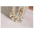Delicate gold-toned pearl flower bracelet with cream-colored pearls and gold horse charm featuring a white enamel daisy