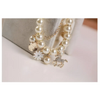 Delicate gold-toned pearl flower bracelet with cream-colored pearls and gold horse charm featuring a white enamel daisy