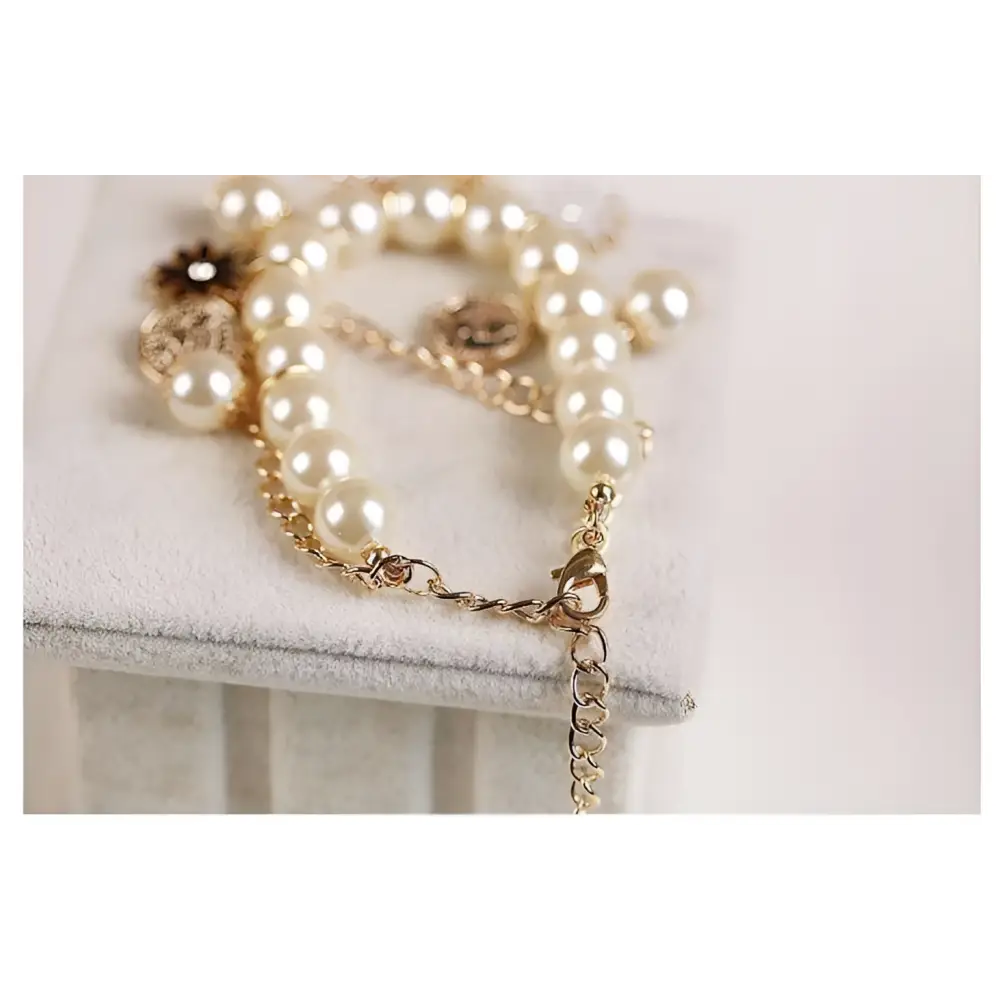 Navy pearl flower bracelet with cream-colored pearls gold-toned chain and gold horse charm detailing