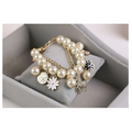 Navy pearl flower bracelet with cream-colored pearls and gold horse charm featuring white flower and silver coin charms