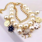 Gold-toned necklace with cream-colored pearls, pearl flower bracelet strands, and a gold horse charm pendant