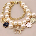 Navy pearl flower bracelet with cream-colored pearls, gold horse charm, navy and white enamel floral accents, and vintage coins