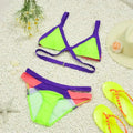 Vibrant geometric fluo bikini featuring a neon green and purple triangle top with crossed straps and pink mesh accents