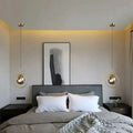Gold-finished nordic modern minimalist glass pendant light with spherical glass shades hangs symmetrically above bed