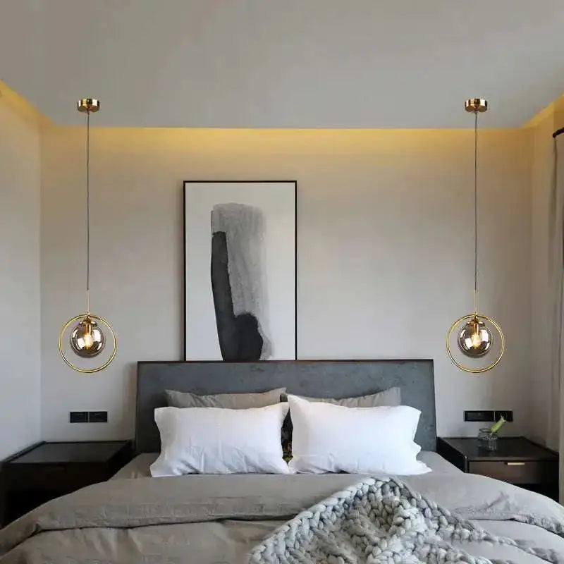 Gold-finished nordic modern minimalist glass pendant light with spherical glass shades hangs symmetrically above bed