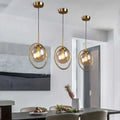 Three nordic modern minimalist glass pendant lights with gold metal frames and amber-tinted globes for indoor use