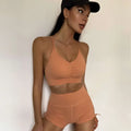 A peach-colored nude sensation waist gathering two piece yoga set with ruched bra top and high-waisted shorts