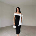 Black off-shoulder color matching elegant cocktail dress with white fabric bow detail and matching white clutch purse