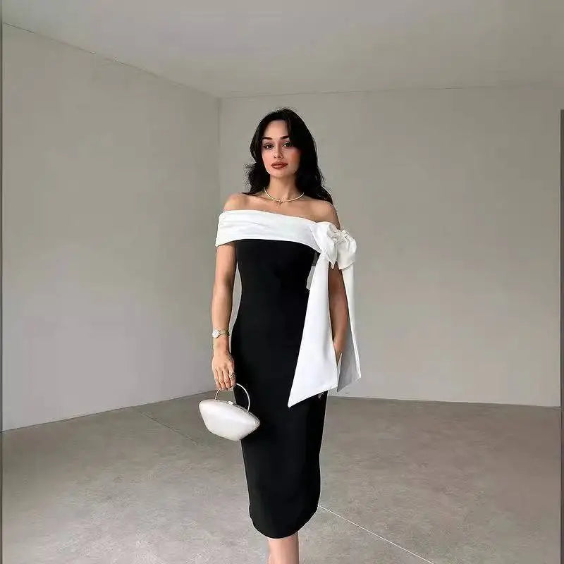 Black off-shoulder color matching elegant cocktail dress with white fabric bow detail and matching white clutch purse