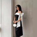 A sleek black and white off-shoulder color matching elegant cocktail dress with a large satin bow at the shoulder