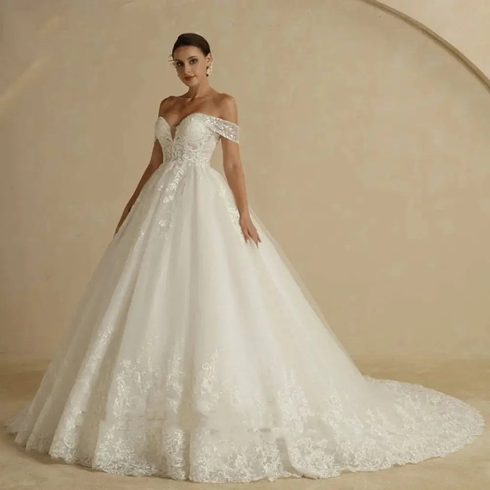 Off-shoulder lace bridal white gown with intricate lace detailing, fitted bodice, and voluminous skirt for weddings