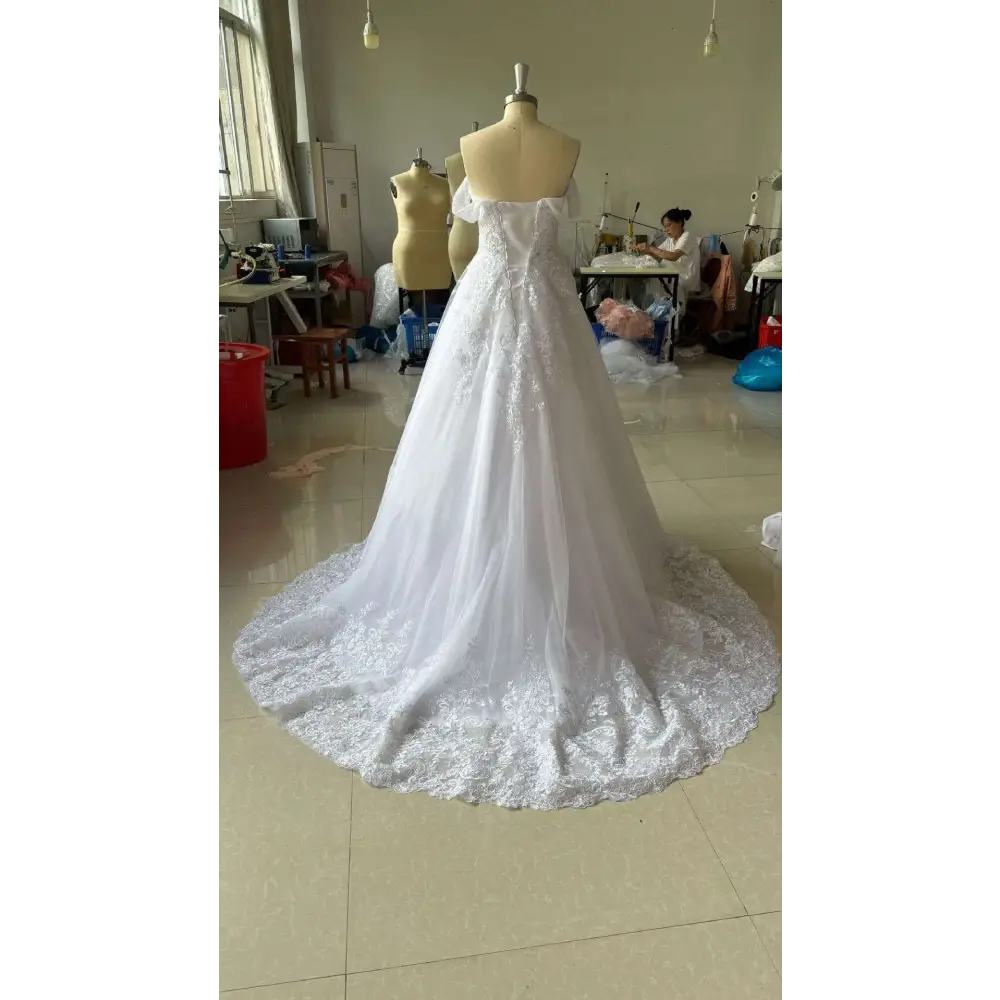 A white off-shoulder lace bridal gown with intricate lace detailing and a flowing skirt displayed on a mannequin