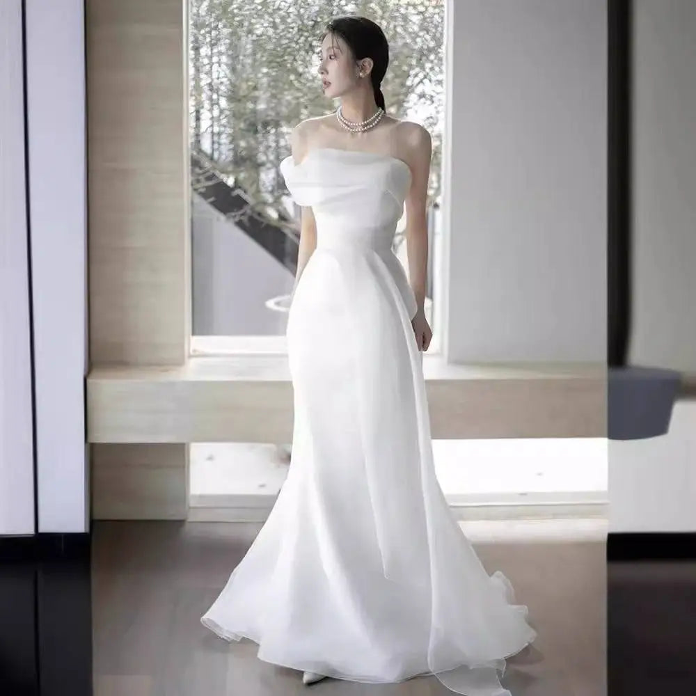 Off-shoulder satin light wedding dress with flowing white fabric, fitted bodice, and flared skirt elegant design