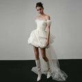 Off-shoulder tulle white wedding dress with structured bodice and voluminous skirt featuring an elegant train