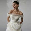 Off-shoulder tulle white wedding dress with ivory satin bodice sheer tulle sleeves and flowing skirt with train