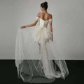 Off-shoulder tulle white wedding dress with structured bodice and layered skirt featuring a train in ivory color
