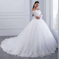 A white off-the-shoulder bridal wedding lace gown with long lace sleeves and a voluminous tulle skirt with floral embroidery