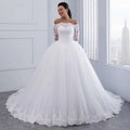White off-the-shoulder bridal wedding lace gown with long lace sleeves and voluminous tulle skirt with floral embroidery