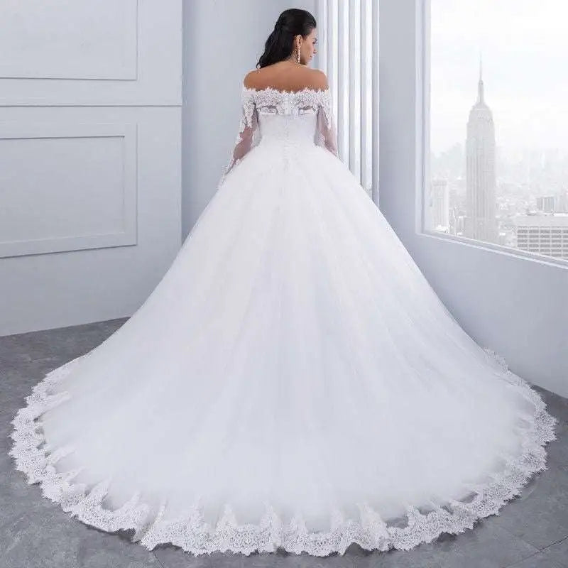 A flowing white off-the-shoulder bridal wedding lace gown with intricate detailing and a delicate tulle skirt