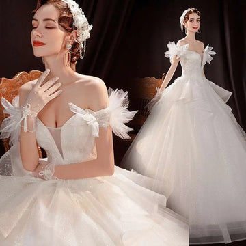 Elegant white wedding dress with off the shoulder lace tulle design and voluminous tulle skirt with embellishments