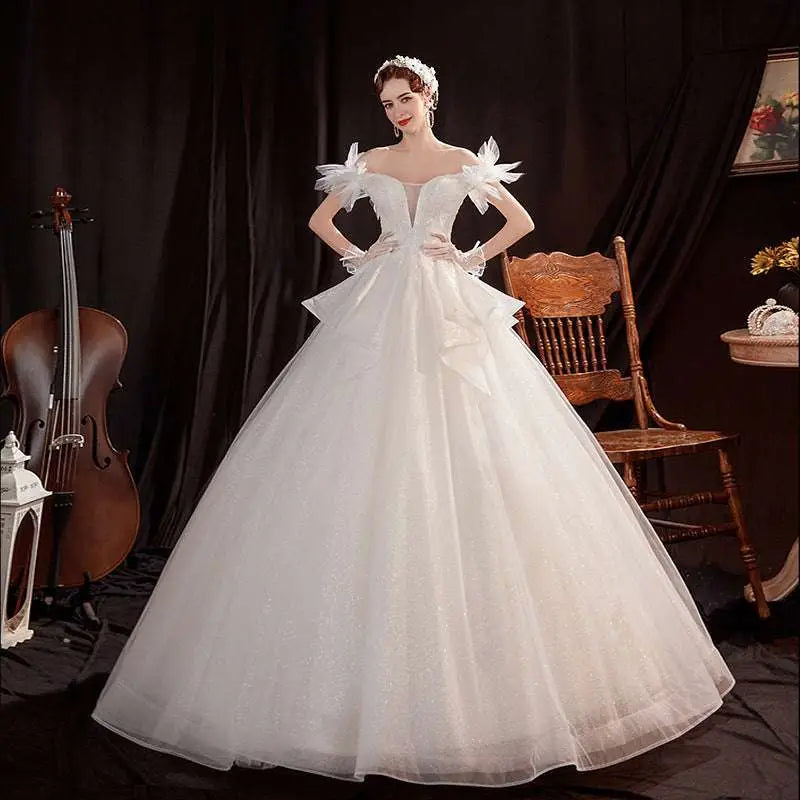 A woman wears an off the shoulder white wedding dress with shoulder lace tulle sleeves and a voluminous tulle skirt