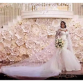 A bride wearing a long sleeves mermaid white wedding dress with off the shoulder neckline and holding a bouquet
