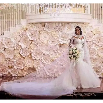 A bride wearing a long sleeves mermaid white wedding dress with off the shoulder neckline and holding a bouquet