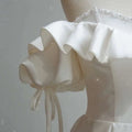 Off the shoulder satin light wedding dress in white with ruffled puffed sleeves and beaded neckline detailing