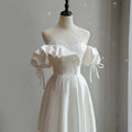 Off the shoulder satin light wedding dress in white with puffed sleeves and delicate bow ties made of satin light fabric