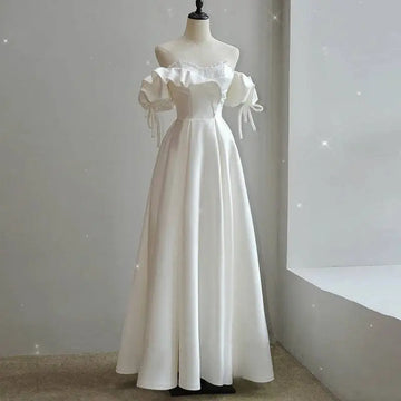 A flowing white satin light wedding dress with off the shoulder design, puffed sleeves, and delicate shoulder ties