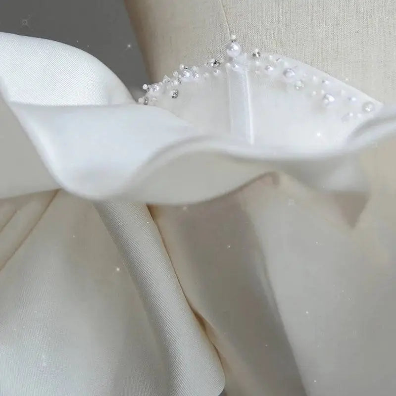 Off the shoulder satin light wedding dress with delicate white satin ruffle adorned with pearls and tiny crystals