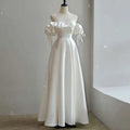 Off the shoulder satin light wedding dress in white with puffed sleeves and delicate tie details