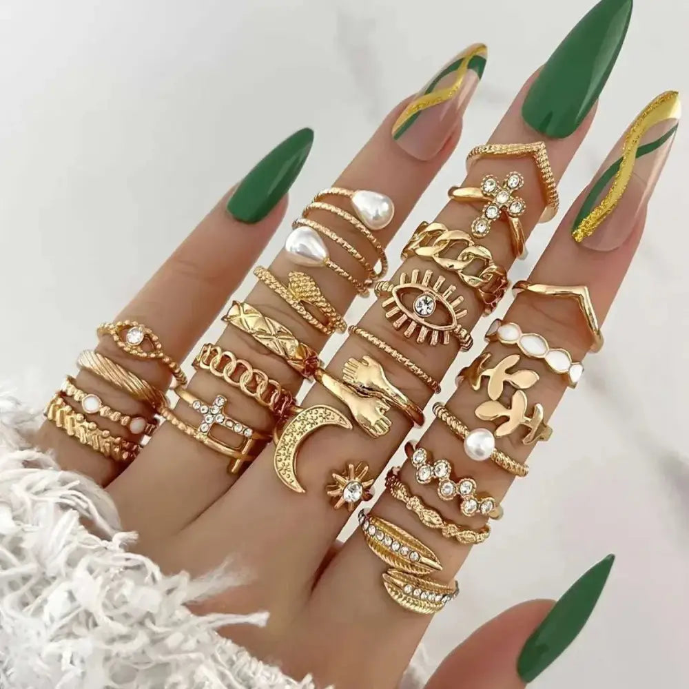 A hand adorned with a silver oil dripping knuckle ring set featuring hearts, butterflies, and pearls designs
