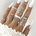 A hand adorned with a silver-toned oil dripping knuckle ring set featuring hearts, pearls, chains, and floral motifs