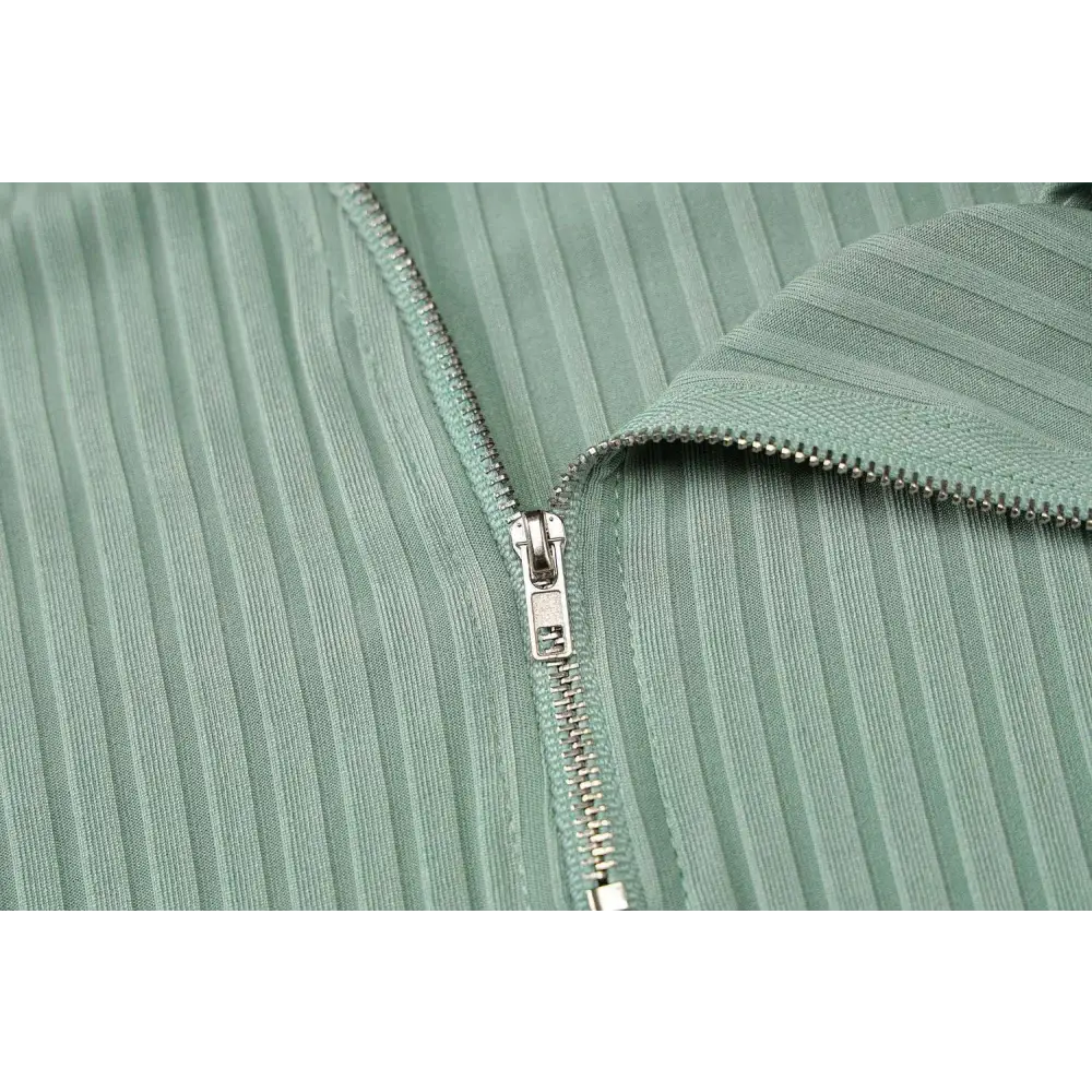 A mint green ribbed fabric zipper with silver metal pull tab on the back of an olive green stripe knitted women sleeveless dress