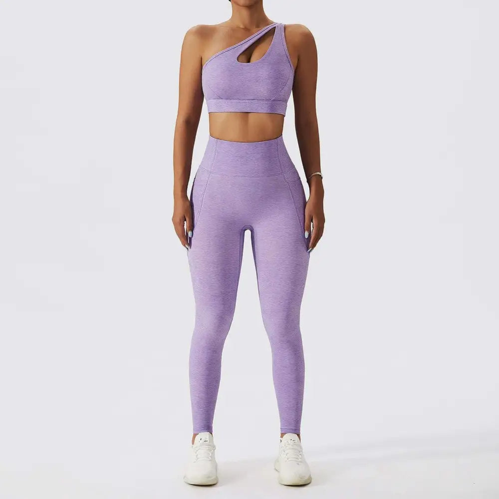 A matching lavender bra fitness suit with one-shoulder crop top cutout and high-waisted leggings in stretchy fabric