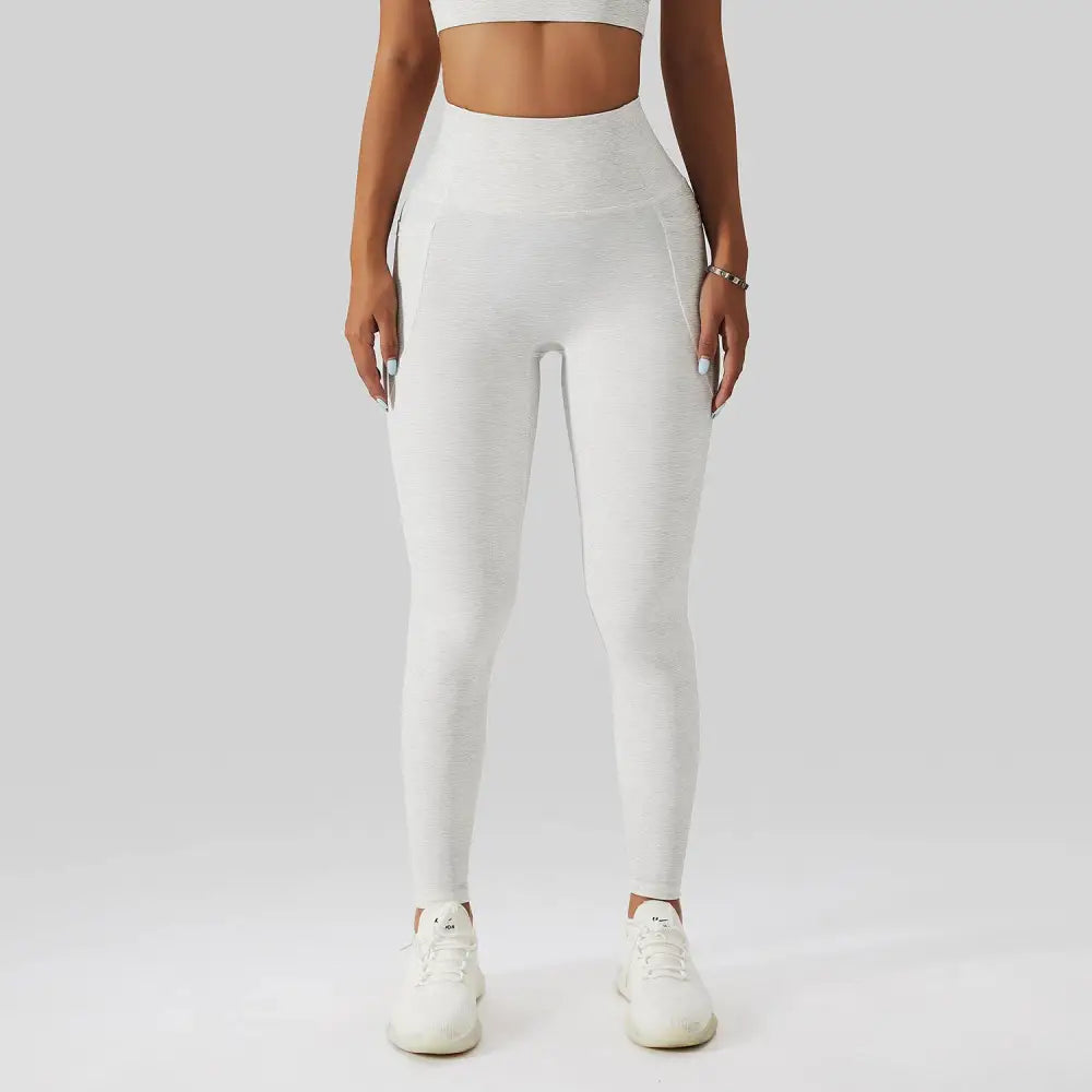 White high-waisted leggings with a textured form-fitting design complementing olive green yoga bra fitness suit with pockets