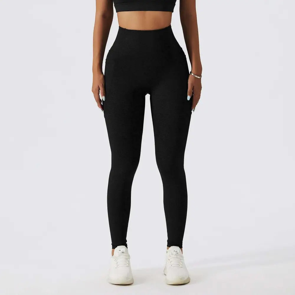 Black high-waisted leggings with smooth form-fitting material and subtle side pockets paired with olive green yoga bra fitness suit