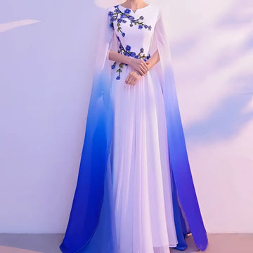 A flowing white floral choral dress with blue embroidery and an ombre cape blue for red song competition events